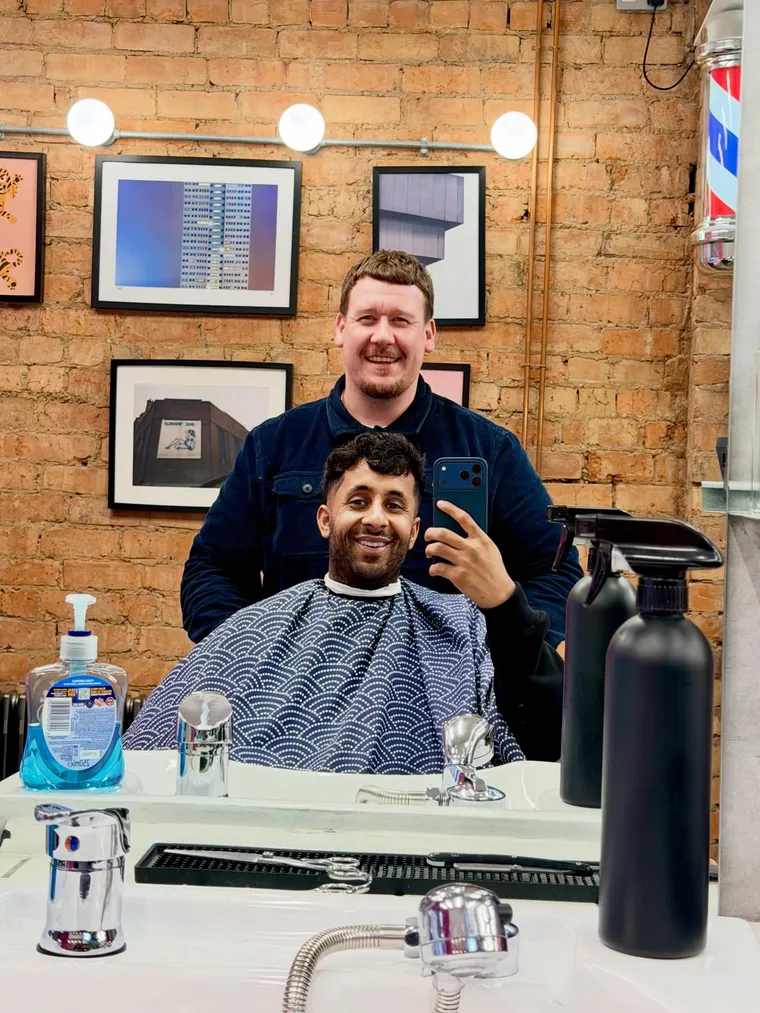 A barber and client mid-appointment inside The Finery